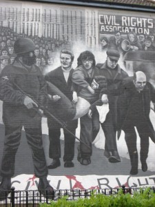 IMG_9664 This mural depicts the banner on the ground over the body of one of the boys while another wounded is carried off for treatment with the priest waving the white flag of surrender - he was shot too.