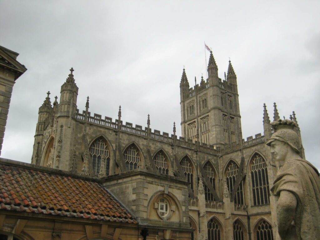 Historic views with the Roman bath and a statue in the foreground and a large cathedral in the background