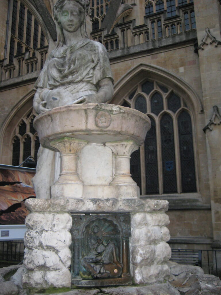 Random statue of a woman next to a stone water feature in Bath, England